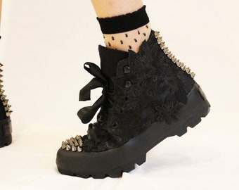 May include: Black lace-up boots with silver studs and a black ribbon tied around the ankle.