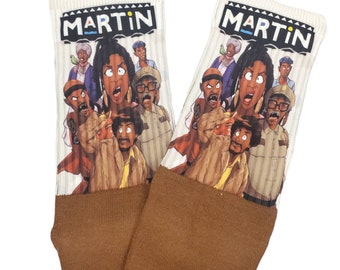 May include: A pair of white socks with a brown cuff. The socks feature a cartoon image of the characters from the TV show "Martin". The socks have the word "MARTIN" printed in black on the top of the socks.