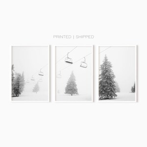 May include: A set of three black and white photographs depicting a snowy landscape with a ski lift and pine trees. The photos are framed in white.