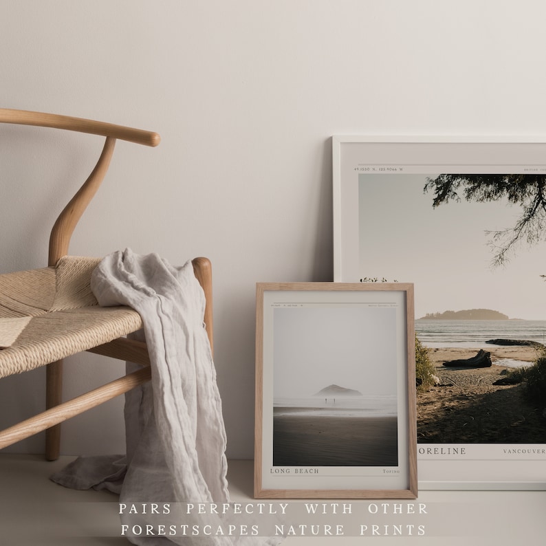 May include: Two framed nature prints with a minimalist aesthetic. The print on the left shows a beach scene with a small island in the distance. The print on the right shows a beach with a tree in the foreground and a mountain in the background. The text on the prints reads "Long Beach" and "ORELINE Vancouver".