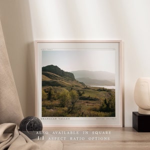 Puede incluir: Una impresi&oacute;n enmarcada de una fotograf&iacute;a de paisaje que presenta una cordillera, un lago y un campo de hierba. El texto "OKANAGAN VALLEY" y "BRITISH COLUMBIA" est&aacute; impreso en la parte inferior de la imagen.