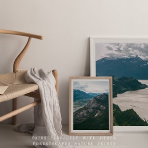May include: Two framed landscape photographs of mountains and water. The smaller photo is a close-up of a mountain range with a valley and a river. The larger photo shows a wider view of a mountain range with a lake in the foreground.