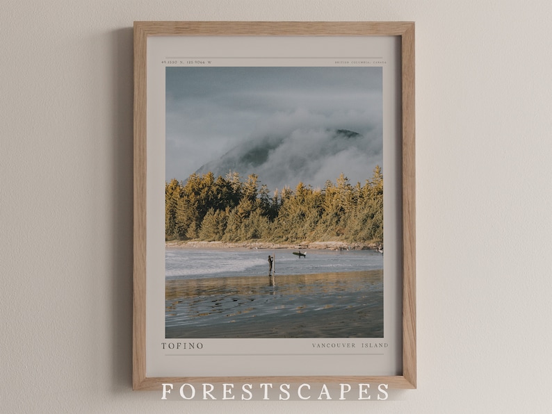 May include: A framed print of a misty mountain landscape with a beach in the foreground. The print features the text "TOFINO VANCOUVER ISLAND FORESTSCAPES" and coordinates.