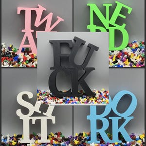 May include: A collage of colorful wooden letters spelling out words. The letters are in various colors, including pink, green, black, white, and blue. The words are displayed on a bed of colorful confetti.