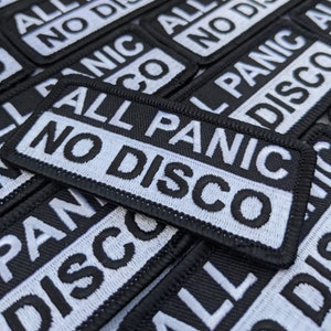 May include: Close-up of several black and white embroidered patches with the text "All No Panic Disco" repeated.