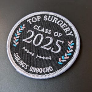 May include: Embroidered circular patch with the text "TOP SURGERY CLASS OF 2025 SIBLINGS UNBOUND" in white on a black background. Features a white border and decorative pink, blue, and white elements.