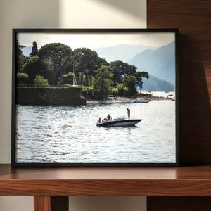 Peut inclure: Photographie encadrée d'une scène de lac avec un bateau à moteur. Le bateau transporte plusieurs personnes. En arrière-plan, des arbres verts luxuriants et des montagnes. L'eau est bleu clair.