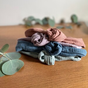 May include: A stack of four fabric headbands in various shades of blue and pink. The headbands are made of a soft, textured fabric and have a knotted design.