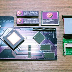 Może przedstawiać: Zestaw komponentów komputerowych, w tym płytka drukowana, karty pamięci i kabel taśmowy. Komponenty zawierają tekst, taki jak "A1200 Kickstart" i "AmigaOS 3.2". Schemat kolorów obejmuje fioletowy, czarny i zielony.