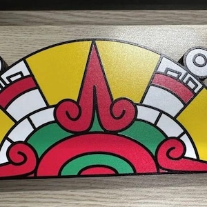 May include: A colorful, semi-circular decorative piece with a geometric design. The piece features a yellow background with red, white, and green accents. Two circular elements are on each end.