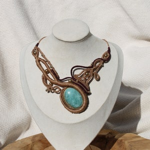 May include: A brown and burgundy macrame necklace with a large oval turquoise gemstone pendant.