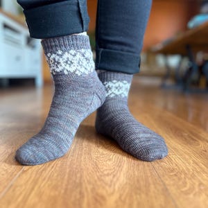 May include: A pair of brown and blue patterned socks with white accents. The socks are made of a soft, knitted fabric and are worn on a person's feet.