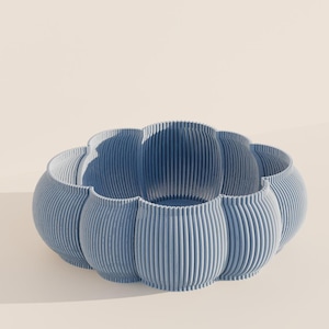 Könnte beinhalten: Eine hellblaue dekorative Schale mit gerippter Textur. Die Schale hat eine einzigartige, wellenförmige Form mit abgerundeten Abschnitten. Die Schale besteht aus einem festen Material und eignet sich zum Halten von Gegenständen oder als dekoratives Stück.