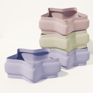 May include: Four pastel-coloured, star-shaped containers are stacked. The colours are lavender, pale green, and pink. The containers have a textured surface and a unique, rounded design. The containers are stacked on top of each other.