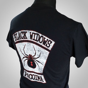 May include: Black t-shirt with a white patch on the back that says "Black Widows" and "Pacoima" with a black spider in the middle.