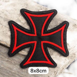 May include: Black and red embroidered cross patch, measuring 8x8cm. The patch features a black cross design with a red border. The patch is suitable for jackets, bags, or other fabric items.
