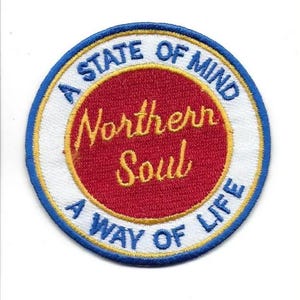 Può includere: Toppa rotonda ricamata con la scritta "A STATE OF MIND Northern Soul A WAY OF LIFE". La toppa presenta un centro rosso con scritte dorate, circondato da un anello bianco, un bordo dorato e un bordo esterno blu.