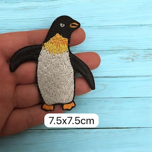 May include: Embroidered penguin patch with black, white, and yellow details. The patch measures 7.5 x 7.5 cm. The penguin has outstretched wings and is ready to be ironed onto clothing or accessories.