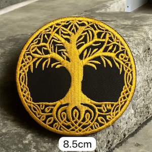 May include: Circular embroidered patch with a gold tree of life design on a black backdrop. The patch measures 8.5cm in diameter, showcasing detailed branches, roots, and a decorative border. A symbol of growth and connection.