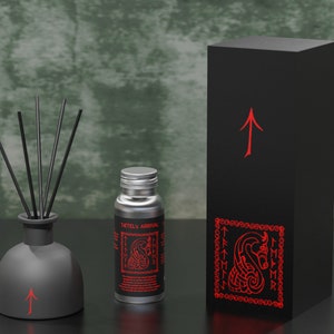 May include: A black diffuser bottle with a red arrow and black reeds. The bottle is next to a silver bottle with a black label that reads "TACTEL'S ARRMAL" and a red dragon design. The silver bottle is next to a black box with a red arrow and a red dragon design.