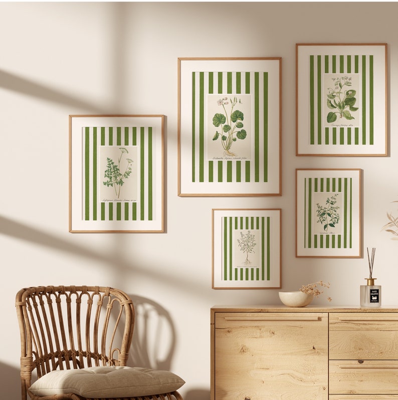 May include: Five framed botanical prints with green and white illustrations of various plants on a white striped background. The frames are all brown wood and are arranged in a staggered pattern on a white wall.