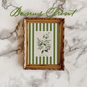 May include: A framed botanical print of a green plant with white flowers. The frame is gold with a green and white striped mat.