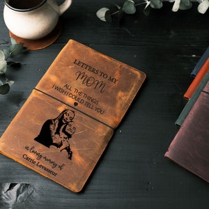 Peut inclure: Un journal en cuir marron avec le texte "Lettres &agrave; ma maman" et "Toutes les choses que j'aimerais te dire" grav&eacute; sur le devant. Le journal a &eacute;galement un &eacute;lastique noir et un petit symbole de c&oelig;ur grav&eacute; sur le devant. Le journal est en m&eacute;moire de Carrie Levasseur.