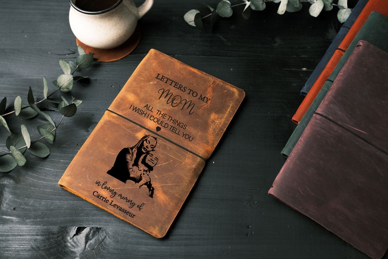 Peut inclure: Un journal en cuir marron avec le texte "Lettres &agrave; ma maman" et "Toutes les choses que j'aimerais te dire" grav&eacute; sur le devant. Le journal a &eacute;galement un &eacute;lastique noir et un petit symbole de c&oelig;ur grav&eacute; sur le devant. Le journal est en m&eacute;moire de Carrie Levasseur.