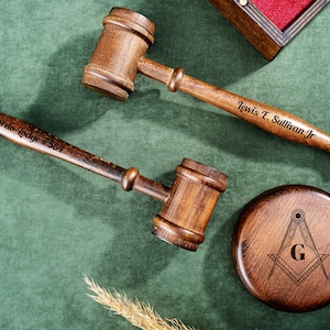 Può includere: Due martelli in legno con testo inciso, "Gordo Lodge #564" e "Lewis E. Sullivan Jr.", e una base in legno con un simbolo massonico intagliato.