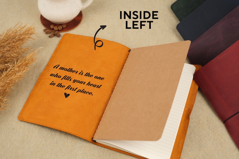 Peut inclure: Un journal reli&eacute; en cuir marron avec une citation sur la couverture : "Une m&egrave;re est celle qui remplit votre c&oelig;ur en premier lieu." Le journal est ouvert sur une page blanche avec du papier lign&eacute;.