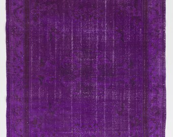May include: A vintage purple rug with a floral pattern and a faded, distressed look. The rug has a dark purple border with a lighter purple center.