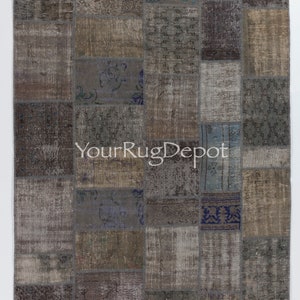 Puede incluir: Una alfombra de patchwork con una variedad de colores y patrones, incluyendo azul, marrón y gris. La alfombra está hecha de materiales reciclados y tiene un aspecto desgastado. La alfombra es rectangular y tiene un borde de flecos. La alfombra está etiquetada como "YourRugDepot".