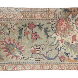 Puede incluir: Cojín rectangular decorativo con diseño de alfombra antigua. El cojín presenta una paleta de colores descoloridos en verde salvia, melocotón y rojos apagados. Patrones florales y geométricos adornan la superficie, creando una estética vintage. Dimensiones: aproximadamente 30 x 61 cm.