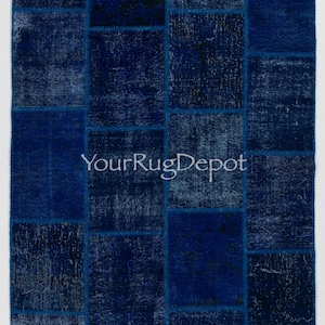 May include: A blue patchwork rug with a variety of shades of blue. The rug is made up of many small squares sewn together. The rug has a distressed look, with some of the squares showing signs of wear and tear. The rug is perfect for adding a touch of bohemian style to any room.