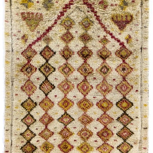 May include: A vintage Moroccan rug with a cream background and a geometric pattern in shades of red, brown, and yellow.