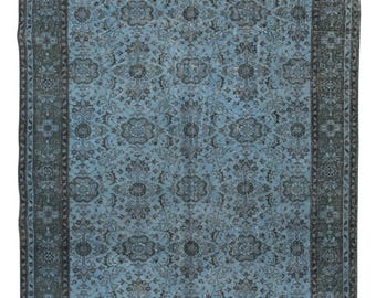 Puede incluir: Una alfombra azul vintage con un patrón floral y un borde oscuro. La alfombra tiene un aspecto desgastado y descolorido, lo que le da un aspecto rústico y antiguo.