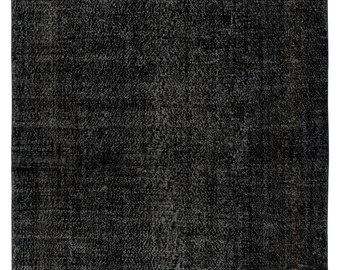May include: A rectangular, dark grey rug with a distressed, textured appearance. The rug has a faded, vintage look, with variations in the grey tones creating a subtle pattern. Suitable for living rooms, bedrooms, or entryways.