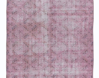 Könnte beinhalten: Ein rosafarbener Vintage-Teppich mit einem verblassten Blumenmuster. Der Teppich hat einen abgenutzten Look und ist aus einem weichen, gewebten Material gefertigt.