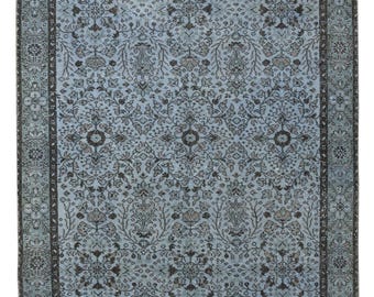 Puede incluir: Una alfombra azul vintage con un patrón floral y un borde oscuro. La alfombra tiene un aspecto descolorido y desgastado.