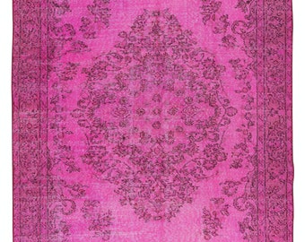 May include: A vintage pink rug with a floral pattern. The rug has a faded look and a distressed texture.