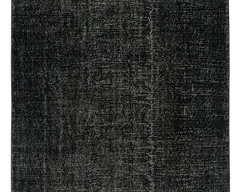 May include: A rectangular rug in black and grey tones, with a distressed appearance. The rug has a textured surface and a faded, vintage aesthetic. It features a central seam and a worn, aged look.