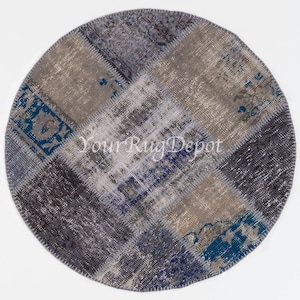 May include: Round patchwork rug with a variety of blue and gray tones. The rug is made of different pieces of fabric sewn together, creating a unique and colorful design. The rug has a fringe border.