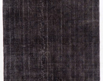 May include: A dark grey vintage rug with a distressed, faded look. The rug has a subtle pattern and a worn texture.