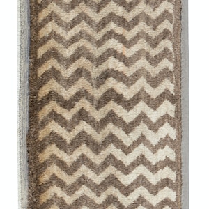 May include: A brown and white rug with a chevron pattern. The rug has a fringe border on all sides.