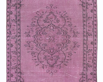 Könnte beinhalten: Ein rechteckiger Teppich im Vintage-Stil in einem zarten Rosa. Der Teppich hat ein zentrales Medaillon-Design und einen detaillierten Rand, beide in einem dunkleren Lilaton. Das Muster umfasst florale und geometrische Elemente.