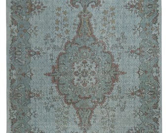 Puede incluir: Una alfombra de estilo vintage con fondo azul claro y un patrón floral detallado en tonos marrones, rosas y verdes.