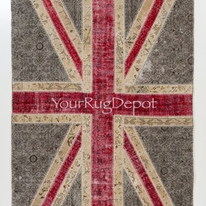 May include: A patchwork rug with a Union Jack design. The rug is made of different fabrics in shades of gray, beige, and red. The rug is a vintage style and has a distressed look.