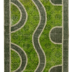 May include: Green patchwork rug with a geometric design. The rug is made of different pieces of fabric sewn together. The rug has a white border.
