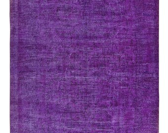 May include: A rectangular, distressed purple rug with a faded, textured appearance. The rug's color is a deep, vibrant purple, with lighter shades creating a worn effect. The rug is likely made of woven material and is suitable for home decor.