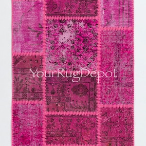 May include: A pink patchwork rug with a variety of floral and geometric patterns. The rug is made from recycled materials and has a unique, hand-woven look.